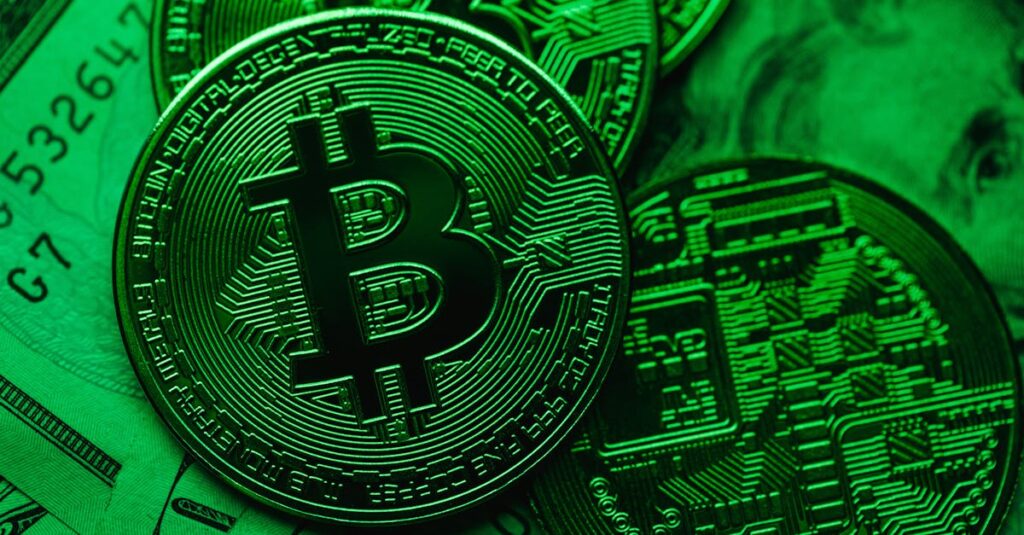 Close-up of Bitcoin coins on paper cash, with a green color tint.